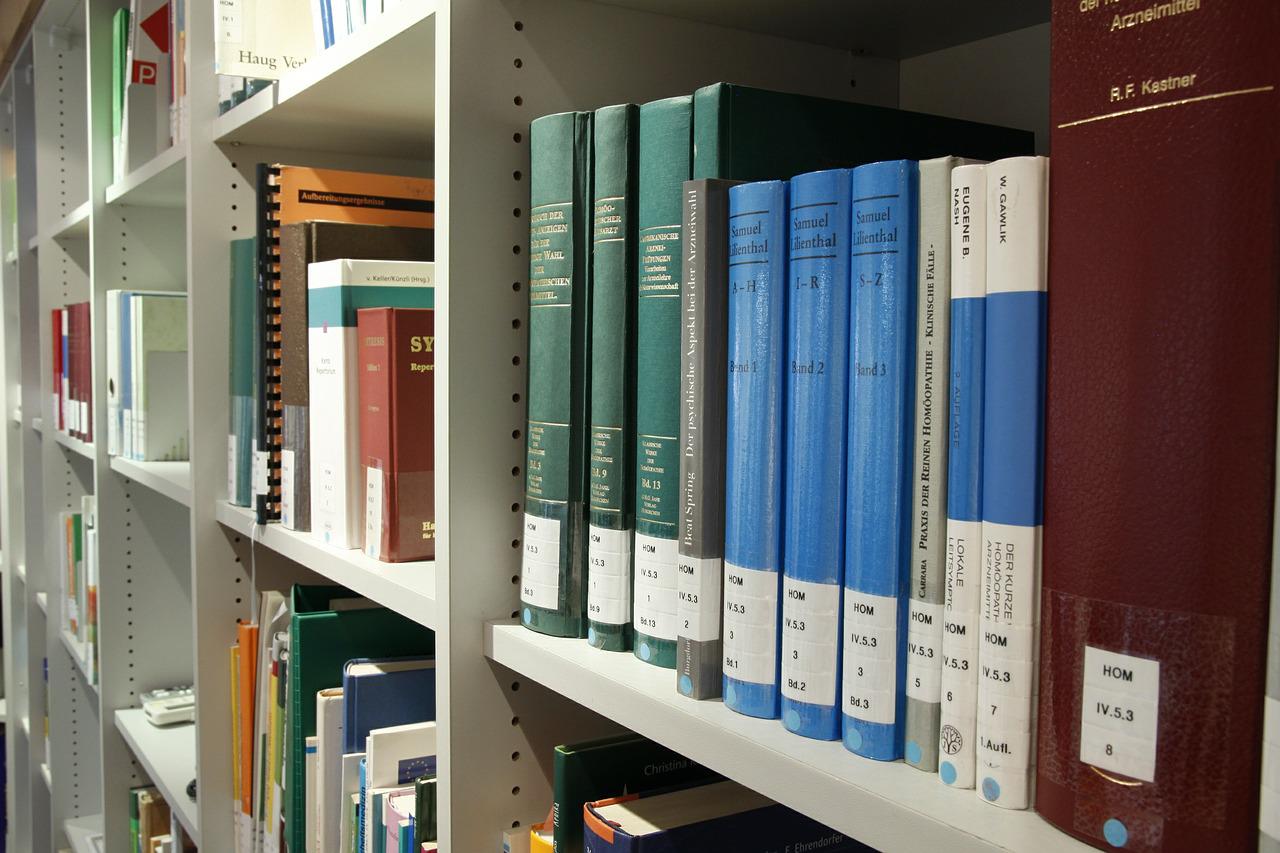 Książki naukowe stojące na półce potrzebne do napisania pracy doktorskiej